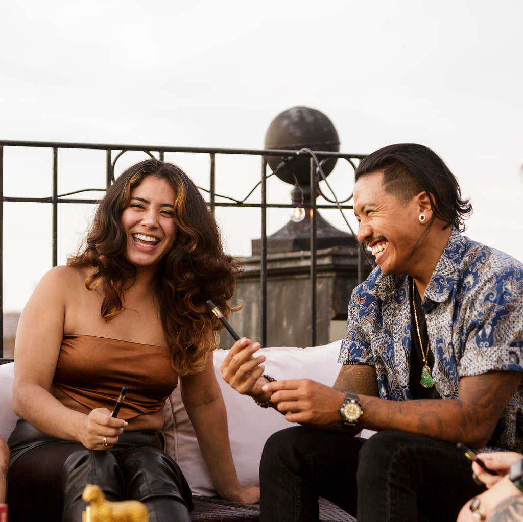 A man and a woman sharing a Golden Tiger vape on a rooftop.