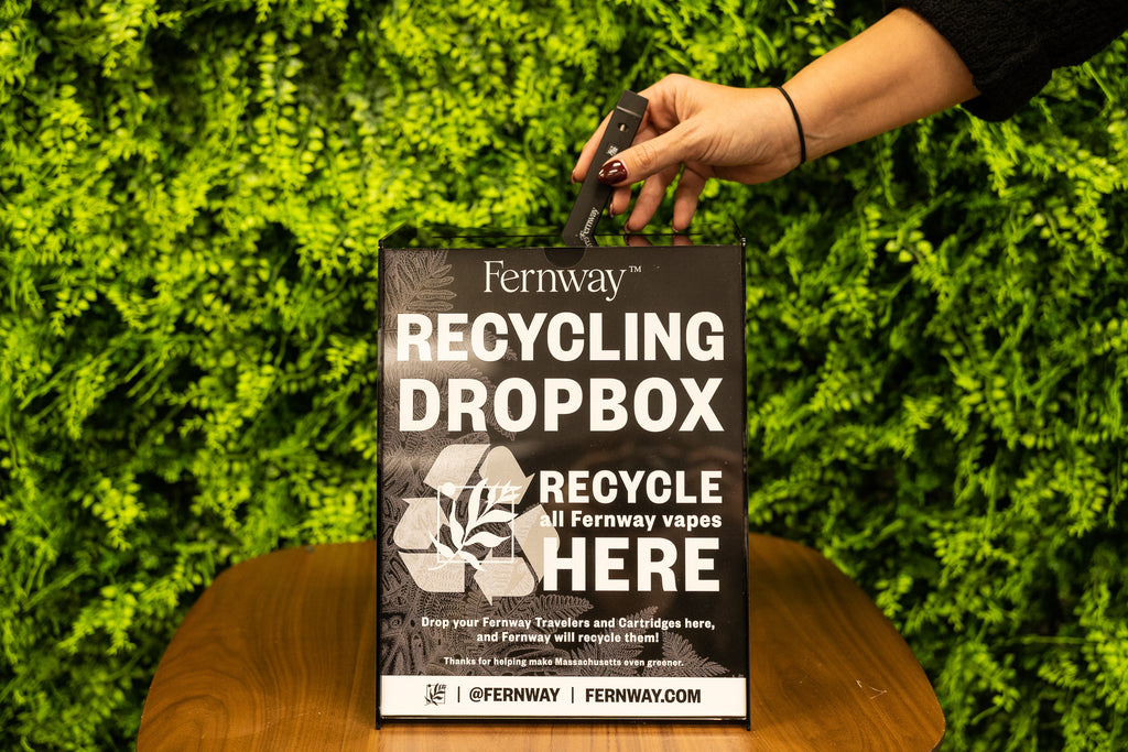 A hand dropping a Fernway vape into a Fernway Recycling Dropbox.