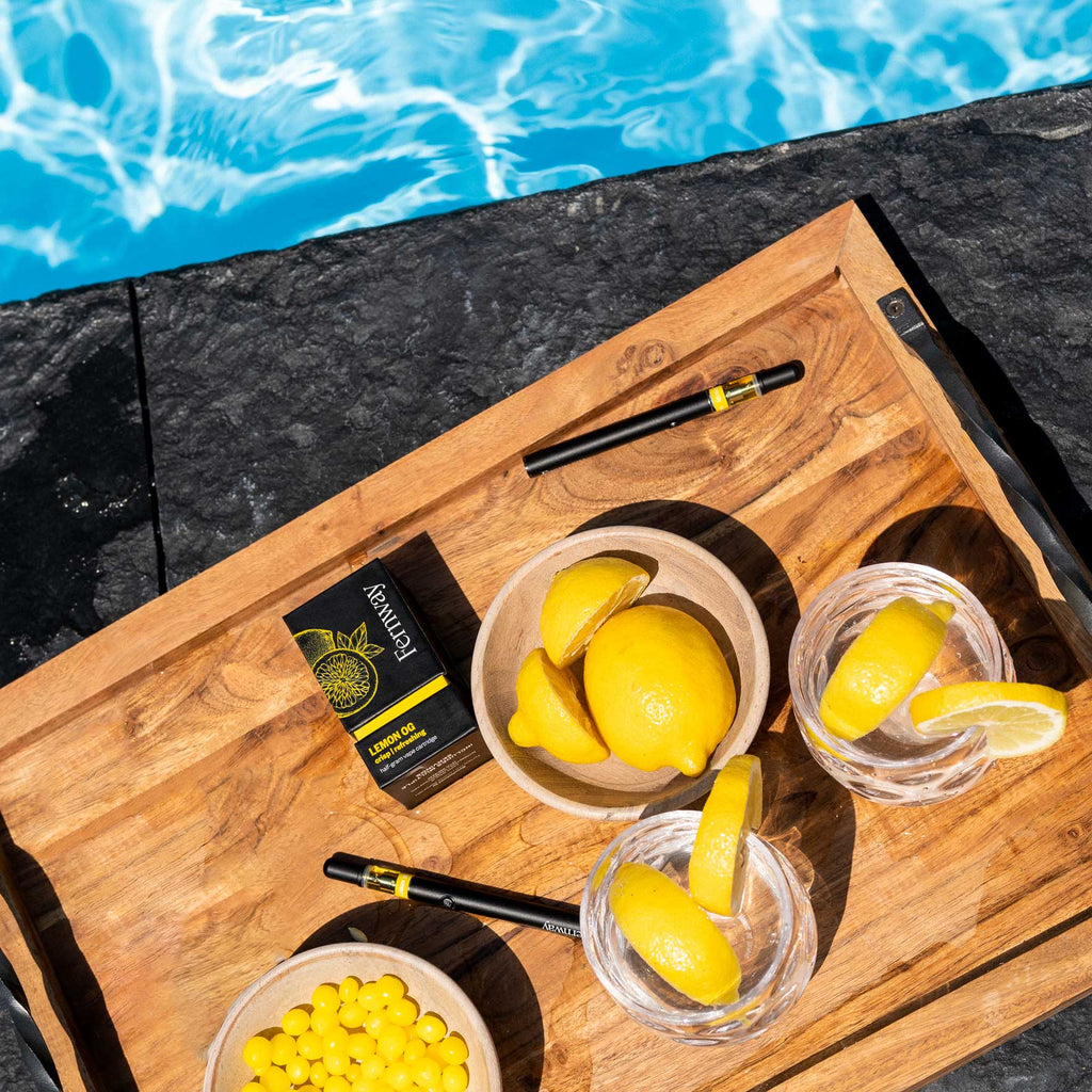 Fernway Lemon OG cartridge and box on a tray with cut up lemons next to a swimming pool.